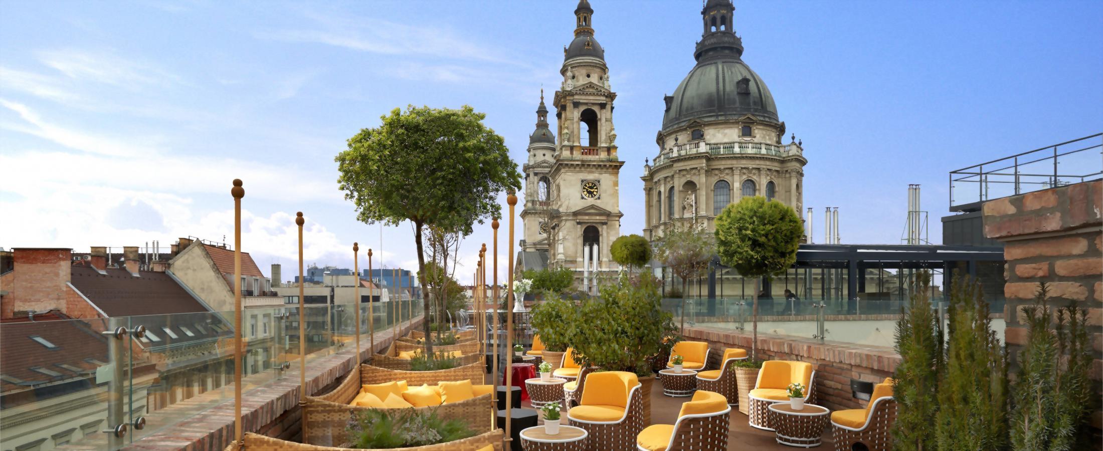 Rooftop filled with seating with yellow cushions and view of St. Stephen's Basilica.